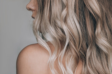 close-up of the wavy blonde hair of a young blonde woman isolated on a gray background. result of co