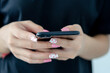 © khunkornStudio - female hand holding a phone with beautiful pink nail polish