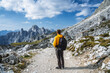 © Igor Tichonow - Man in yellow jacket hiking in Tre Cime National park. Cadini di Misurina in the background. Dolomites, Italy, Europe