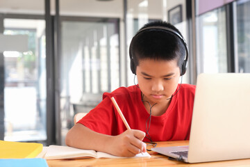 Young collage student using computer and mobile device studying online.