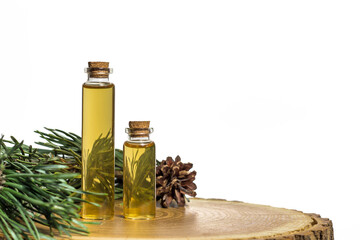 Two glass jars with yellow oil and pine plant extract on a tree cut. White background. Place for inscriptions and text.