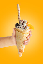 Crepe With Mango In Hand On Yellow Background