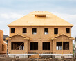 A residential frame house construction project showing the engineered truss roof rafters and oriented strand chip board engineered wall sheathing