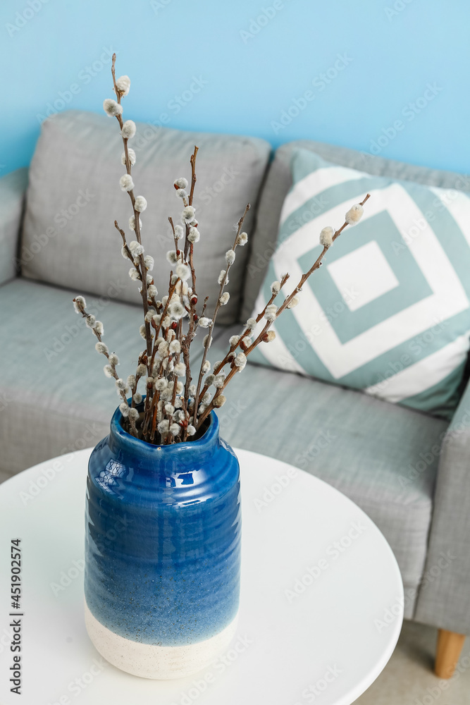Vase with willow branches on table in room
