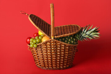 Basket with fresh fruits on color background