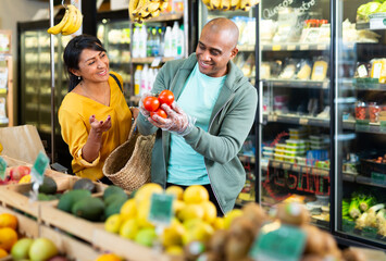 Married couple choosing ripe tomatoes at grocery store