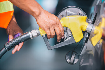 Car refueling on the petrol station. male employees controlled the fuel pump with Fuel nozzles adding gasoline fuel in car at a pump gas station.