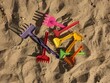a bunch of multi-colored children's rakes in the sand. illustration for the proverb step on the same rake