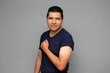 Happy Latino adult man shows his arm that just received the Covid-19 vaccine in the new normal for the coronavirus pandemic
