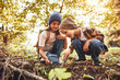 © JenkoAtaman - Two little kids in warm hats with backpacks examining tree bark through magnifying glass in forest