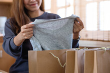 A Woman Picking Clothes From Shopping Bag For Delivery And Online Shopping Concept