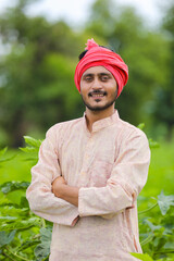 Wall Mural - Young Indian farmer standing at green agriculture field.