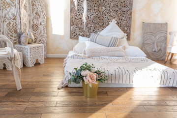 modern interior of a bright room in a two-storey apartment with decorative items in bali style with a balcony. white walls, wood floors and vintage furniture