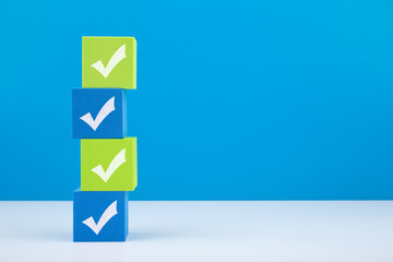 four checkmarks on green and blue blocks on white table against blue background with copy space. con