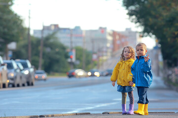 Wall Mural - children brother and sister play autumn rain / October weather little children walk in the city