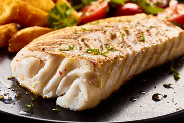 Sticker - Closeup of palatable fish fillet with seasoning served on a black plate