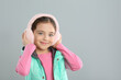 © New Africa - Cute girl wearing stylish earmuffs on grey background. Space for text