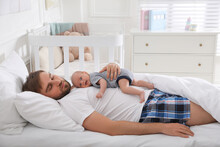 Tired Young Father Sleeping With His Baby In Bed At Home