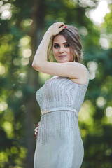 Poster - Pretty young woman in an ivory color dress is posing in the park