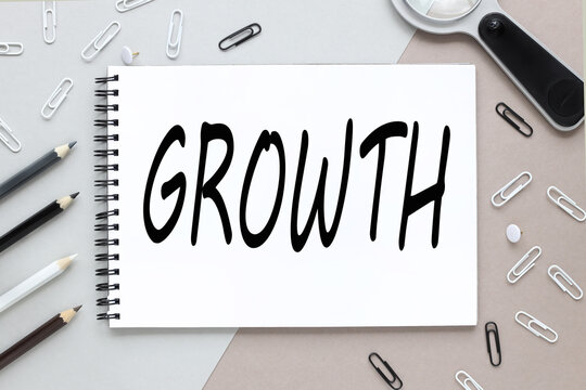 GROWTH. notepad on a background of different colors. brown, gray. paper clips black and white