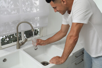 Canvas Print - Man filling glass with water from tap at home