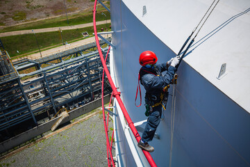 Wall Mural - Focus top view male worker down height tank roof rope access safety inspection of thickness storage tank gas