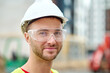 © zinkevych - Pleased attractive builder in safety goggles posing for the camera
