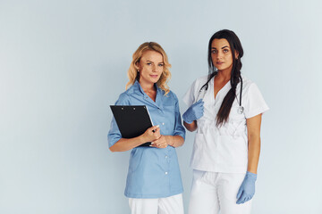 Two doctors in uniform standing indoors and working together