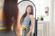 Young woman measuring waist with tape  and standing in front of mirror. Weight lossconcept