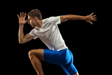 Close-up portrait muscular, sportive man, male athlete, runner training isolated on dark studio background with spotlight. Concept of action, motion, youth, healthy lifestyle.