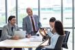 © Pornsak - Businesspeople discussing together in the conference room during meeting at the office.