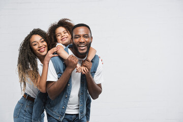 happy african american family looking at camera while hugging on grey