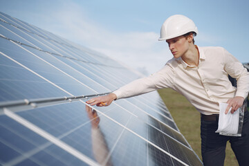 Wall Mural - Businessman in a white helmet near solar battery