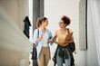 © Drazen - Happy female students talk while walking through university hallway.
