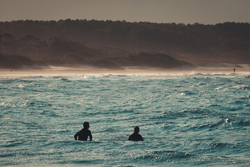 silhouette of two surfers in the water