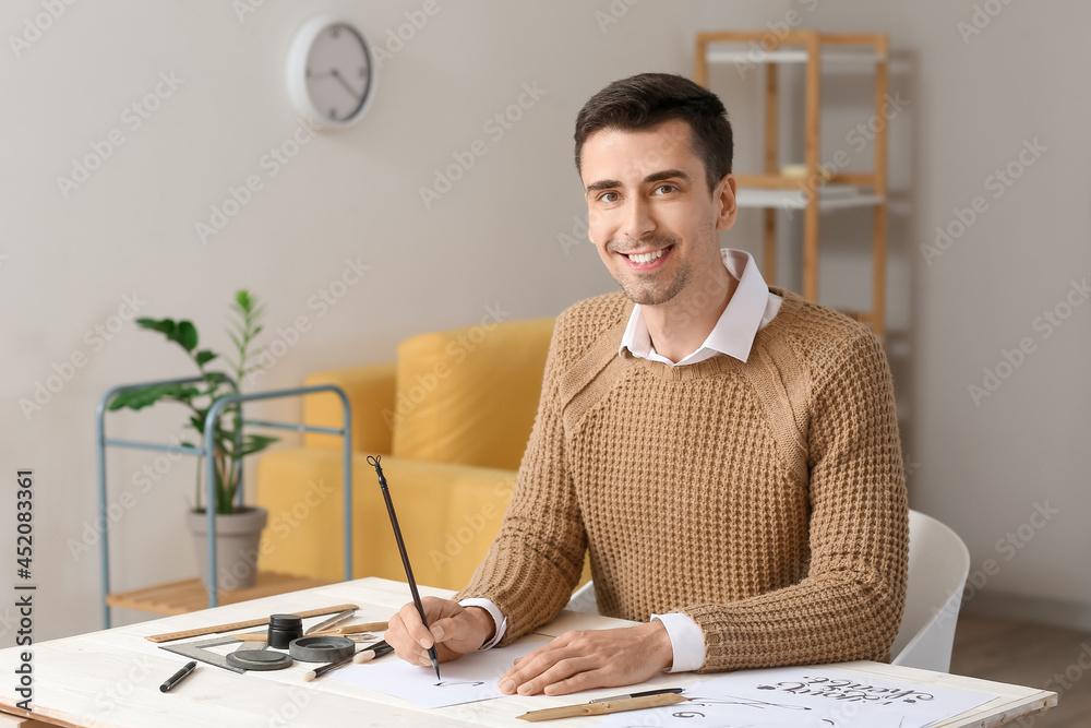 Young male calligrapher working in office