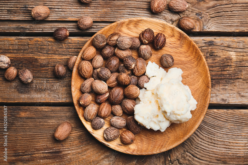 Plate with shea butter and nuts on wooden background