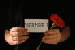 Woman holding paper with date of National Day of Prayer and Remembrance for the Victims of the Terrorist Attacks on dark background