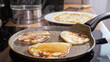 © lenblr - Close-up of mini pancakes on a hot frying pan.