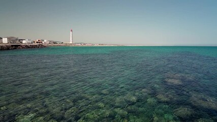 Wall Mural - Ilha de Farol. Algarve. Portugal. The calm ocean is turquoise. The lighthouse in the background