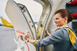 Joyous flight attendant closing the plug door before the take-off