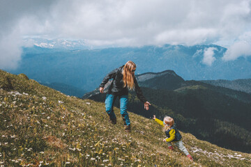 Mother hiking with child in mountains active vacations travel outdoor healthy lifestyle adventurous parent with baby