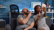 © DC Studio - Joyful interracial couple taking selfies together at home. Young mixed race partners sitting on sofa in living room capturing pictures on smartphone. Multi ethnic people using technology