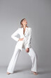 beautiful young woman in a trendy white suit stands in a dynamic pose,
