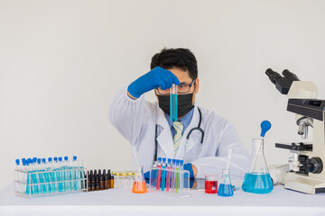 Blue gloved scientist hands holding a bottle with laboratory glassware in a doctor's science lab research and development concept.