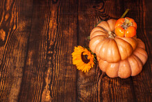 Pyramid Of Pumpkins With Sunflower And Persimmon On A Brown Wooden Background