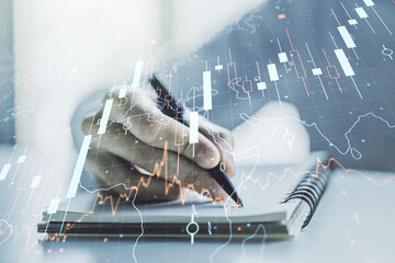 Poster - Double exposure of abstract creative financial diagram with world map and with man hand writing in notepad on background, banking and accounting concept
