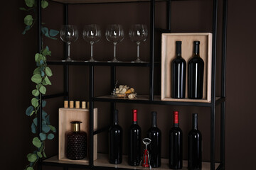 Wall Mural - Rack with bottles of wine and glasses near brown wall