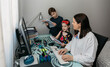© David Pereiras - Woman teleworking and reviewing her children's homework. Selective focus on children in background