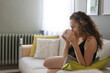 © dragonstock - Young woman drinking cup of coffee sitting on sofa